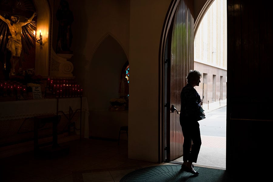 A figure leaves a church veiled in darkness 